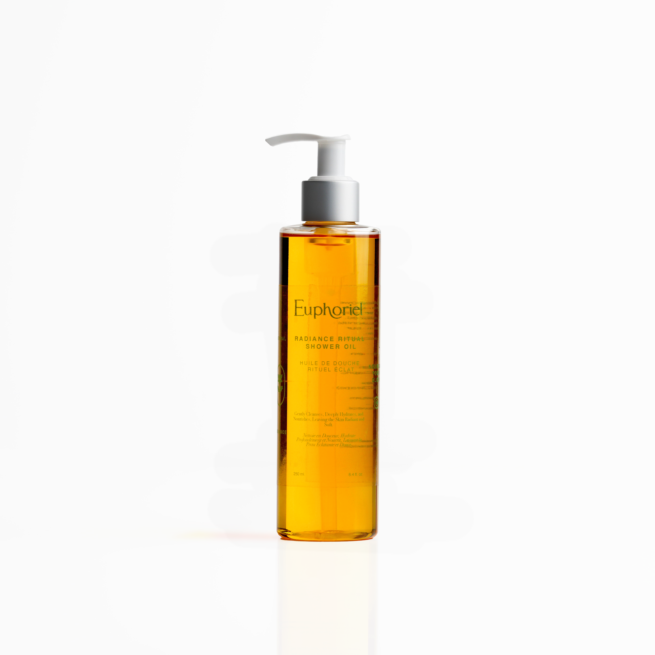 A pump bottle of Radiance Ritual Shower Oil with a yellow hue.
